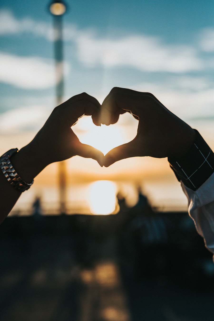 Two hands forming a heart at sunset